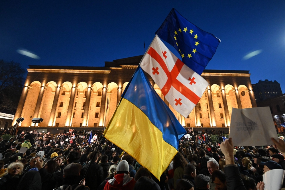 A protesters wave the Georgian, Ukrainian and European flags during a demonstration called by Georgian opposition and civil society groups outside Georgia's Parliament in Tbilisi on March 8, 2023.  (Photo by Vano SHLAMOV / AFP)