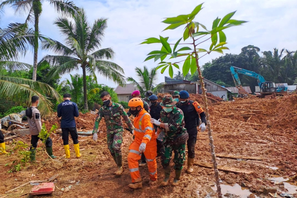 This handout picture taken on March 8, 2023 and released on March 9, 2023 by ministry of communication and information shows rescue team evacuate the body of a victim that was found buried by a landslide at Pangkalan village, in Natuna Islands. (Photo by Handout / Natuna ministry of communication / AFP)