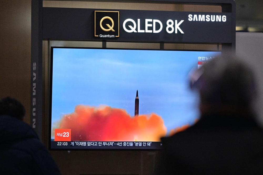 A man walks past a television showing a news broadcast with file footage of a North Korean missile test, at a railway station in Seoul on March 9, 2023. - North Korea fired a short-range ballistic missile on March 9, Seoul's military said, Pyongyang's latest show of force just days before South Korea and the United States kick off major joint military exercises. (Photo by Anthony WALLACE / AFP)