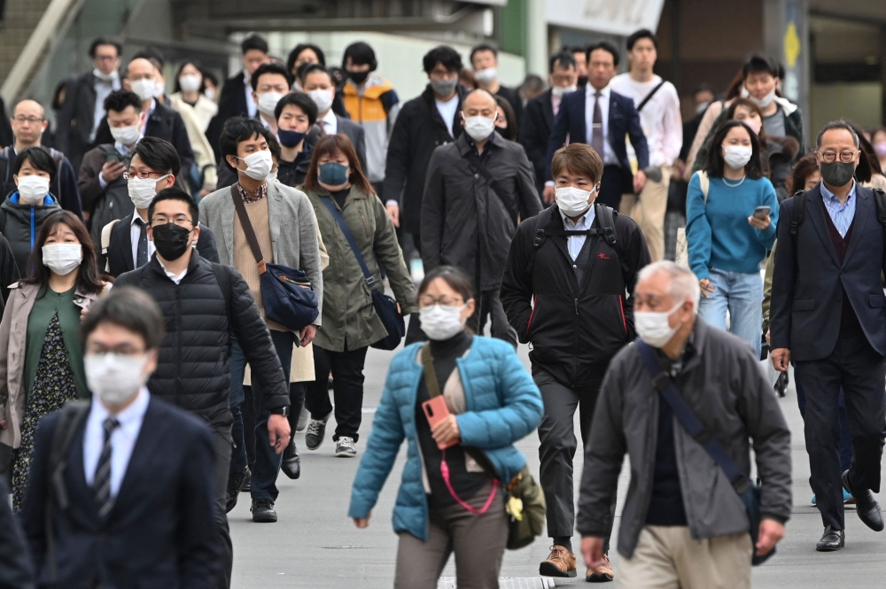 Commuters walk on a street in Shinjuku district of Tokyo on March 13, 2023. Photo by Kazuhiro NOGI / AFP