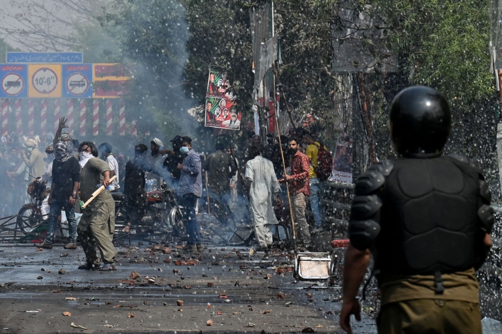 Supporters of former prime minister Imran Khan clash with riot police near Khan's house to prevent officers from arresting him, in Lahore on March 15, 2023. (Photo by Arif ALI / AFP)