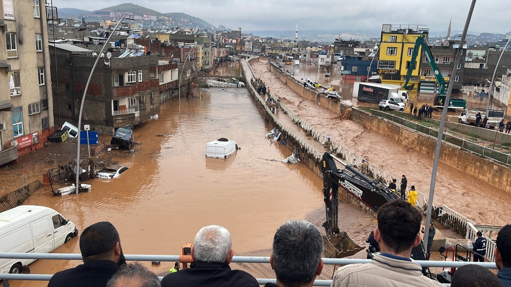 People stand at a high pont looking down at the flood waters in Sanliurfa, southeastern Turkey on March 15, 2023. (AFP)