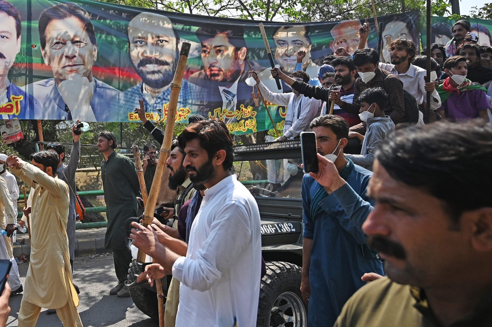 Supporters of former Pakistan's prime minister Imran Khan shout slogans as they march towards Khan's residence in Lahore on March 16, 2023. (Photo by Aamir QURESHI / AFP)