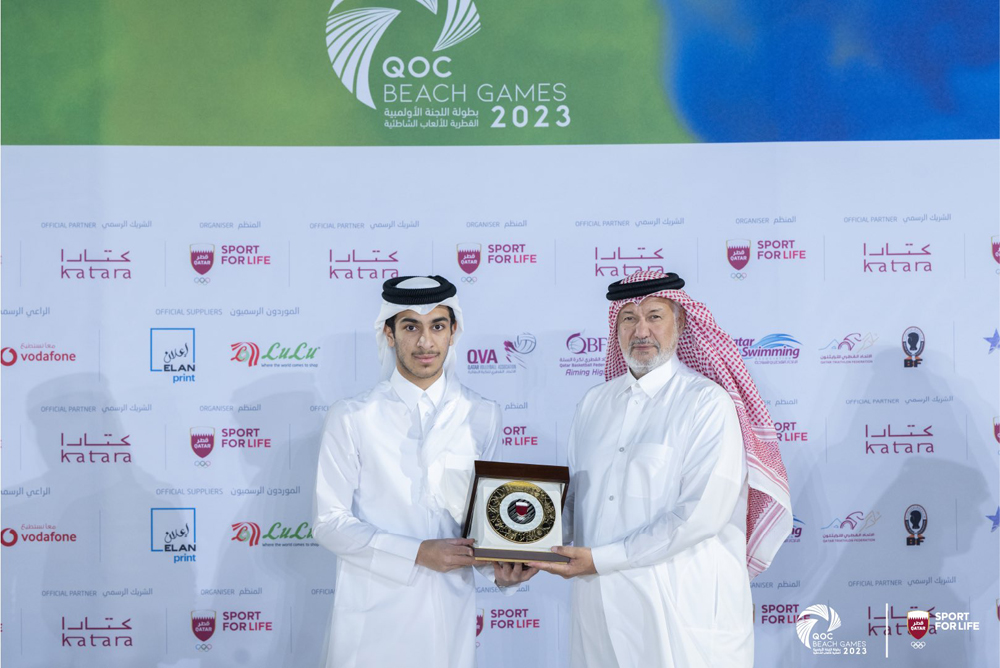 Qatar Olympic Committee First Vice President Mohamed bin Yousef Al Mana presents a memento to a participant.