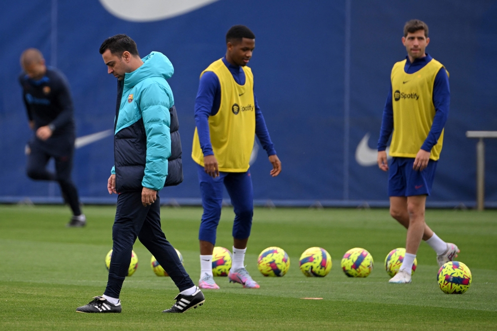 Barcelona's Spanish coach Xavi (L) attend a training session at the Joan Gamper training ground in Sant Joan Despi, on March 18, 2023, on the eve of the Spanish league 'El Clasico' football match between Barcelona and Real Madrid. (Photo by LLUIS GENE / AFP)