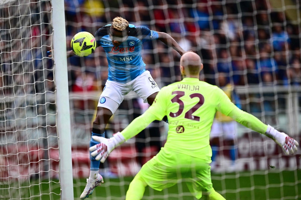Napoli's Nigerian forward Victor Osimhen scores a header and his side's third goal, past Torino's Serbian goalkeeper Vanja Milinkovic-Savic during the Italian Serie A football match between Torino and Napoli on March 19, 2023 at the Olympic stadium in Turin. (Photo by Marco BERTORELLO / AFP)