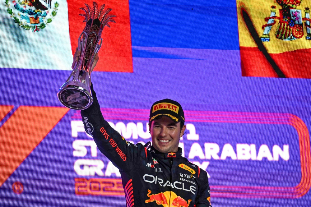 Red Bull Racing's Mexican driver Sergio Perez celebrates with the trophy on the podium after winning the Saudi Arabia Formula One Grand Prix at the Jeddah Corniche Circuit in Jeddah on March 19, 2023. (Photo by Ben Stansall / AFP)
 