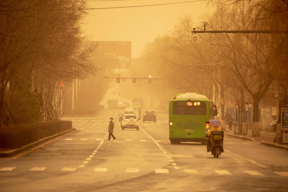People commute on a street during a sandstorm in Jilin, in China's northeastern Jilin province on March 22, 2023. (Photo by AFP) / China OUT