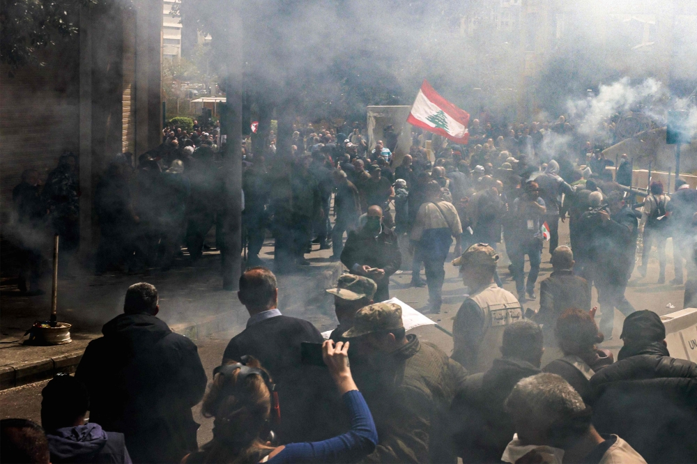 Tear gas fumes fill the air as retired Lebanese army and security forces veterans attempt to break into the government palace premises in the centre of Beirut on March 22, 2023 . (Photo by Joseph Eid / AFP)
