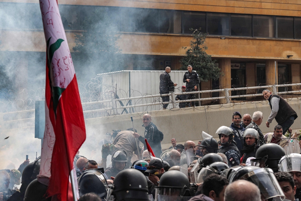 Security offices in the background watch as retired Lebanese army and security forces veterans gather to protest outside the government palace headquarters in the centre of Beirut on March 22, 2023, demanding inflation-adjustments to their pensions. (Photo by JOSEPH EID / AFP)