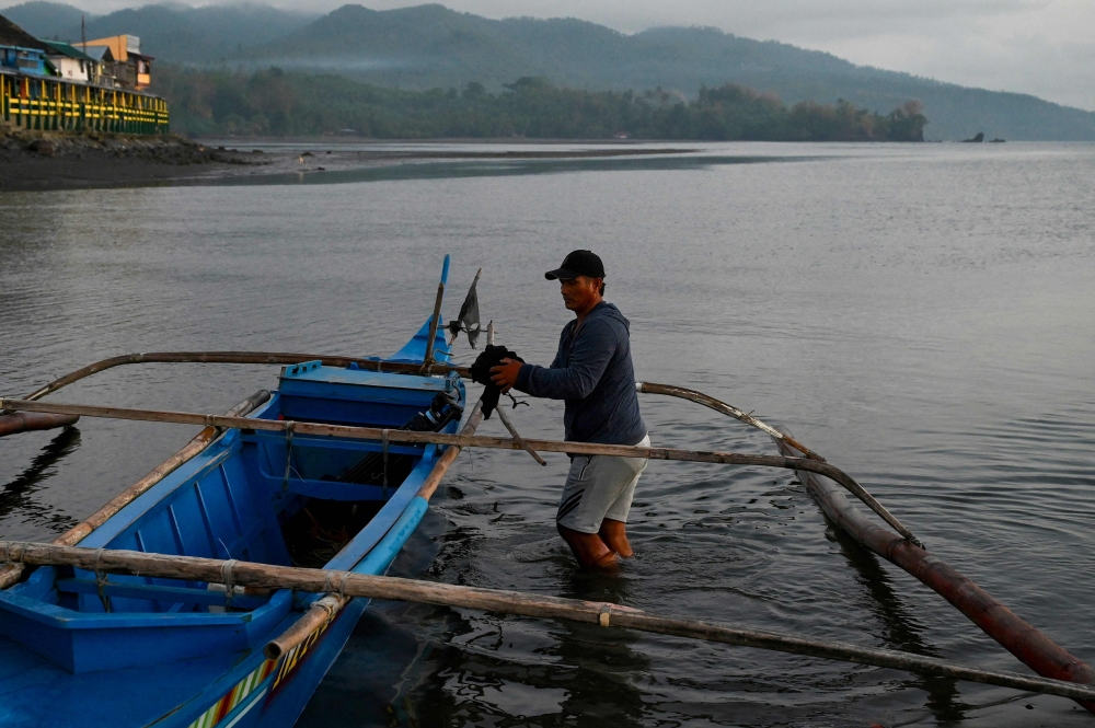 In this picture taken on March 22, 2023, a fisherman prepares his boat to transport passengers in Pola, Oriental Mindoro province, one of the areas affected by an oil spill from the sunken tanker Princess Empress. Photo by JAM STA ROSA / AFP