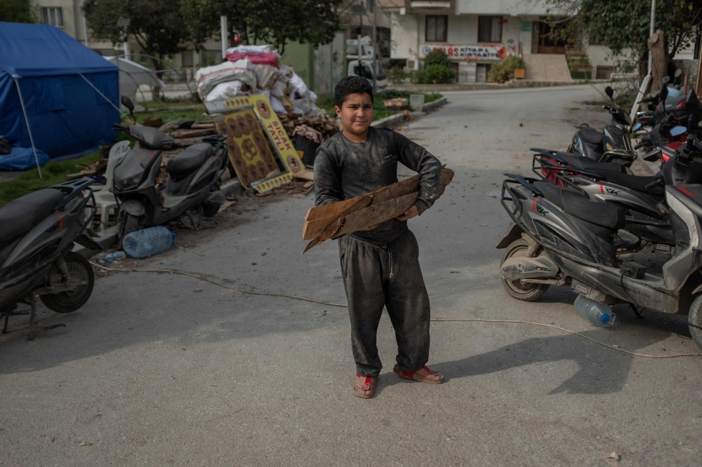 A Syrian boy carries woods for a bakery in the centre of Hatay, on March 28, 2023, after a 7.8-magnitude earthquake on February 6, 2023 killed more than 50,000 in southeastern Turkey and nearly 6,000 over the border in Syria, leaving entire cities in ruins. (Photo by BULENT KILIC / AFP)