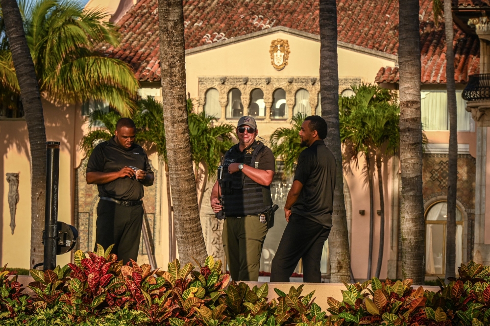 A secret service agent stands with security guards outside of the Mar-a-Lago Club, home of former US President Donald Trump, in Palm Beach, Florida, on April 1, 2023. - Trump is expected to surrender to the authorities in New York on April 4, 2023 to face charges over a hush-money payment to porn star Stormy Daniels. (Photo by Giorgio Viera / AFP)