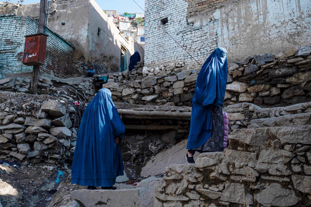 :Afghan burqa-clad women climb a stony path in the Sh?r B?z?r area of Kabul on April 6, 2023. (Photo by Wakil KOHSAR / AFP)
