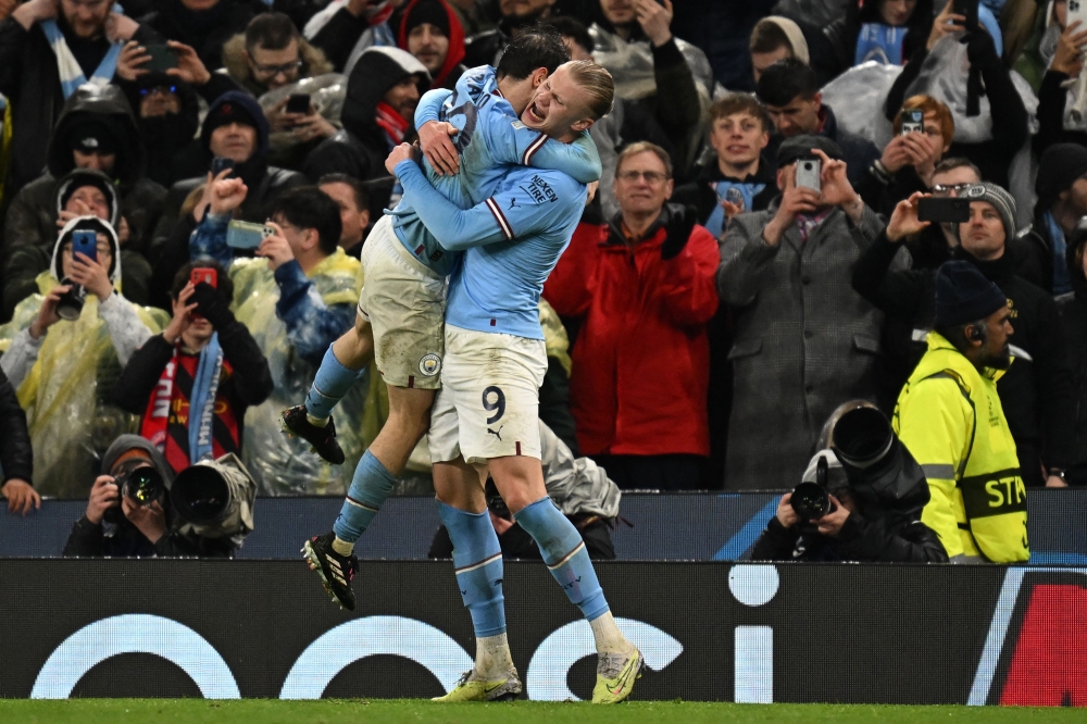 Manchester City's Norwegian striker Erling Haaland (R) celebrates with Manchester City's Portuguese midfielder Bernardo Silva (L) after scoring their third goal during the UEFA Champions League quarter final, first leg football match between Manchester City and Bayern Munich at the Etihad Stadium in Manchester, north-west England, on April 11, 2023. (Photo by Paul ELLIS / AFP)
