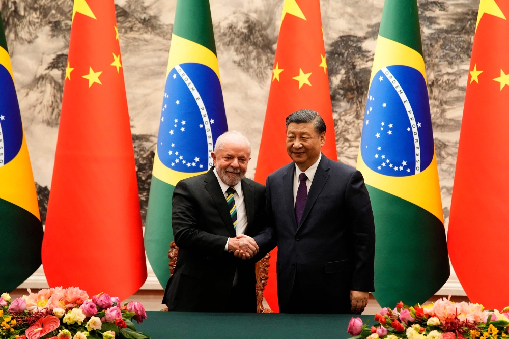 Chinese President Xi Jinping (right) and Brazil's President Luiz Inacio Lula da Silva shake hands after a signing ceremony at the Great Hall of the People in Beijing on April 14, 2023. (Photo by Ken Ishii / POOL / AFP)