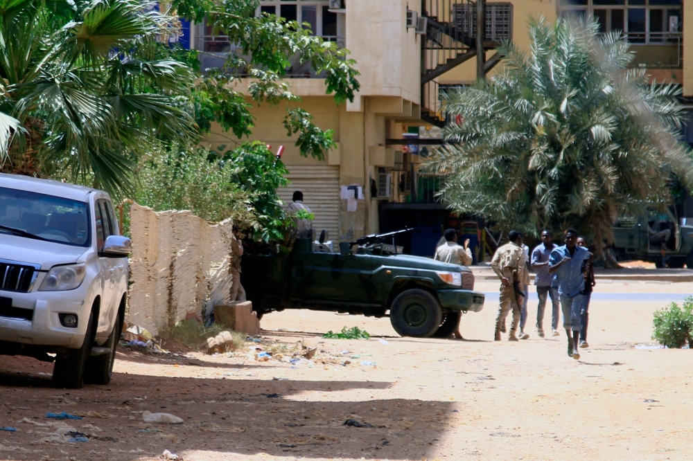 People walk past a military vehicle in Khartoum on April 15, 2023, amid reported clashes in the city  Photo by AFP