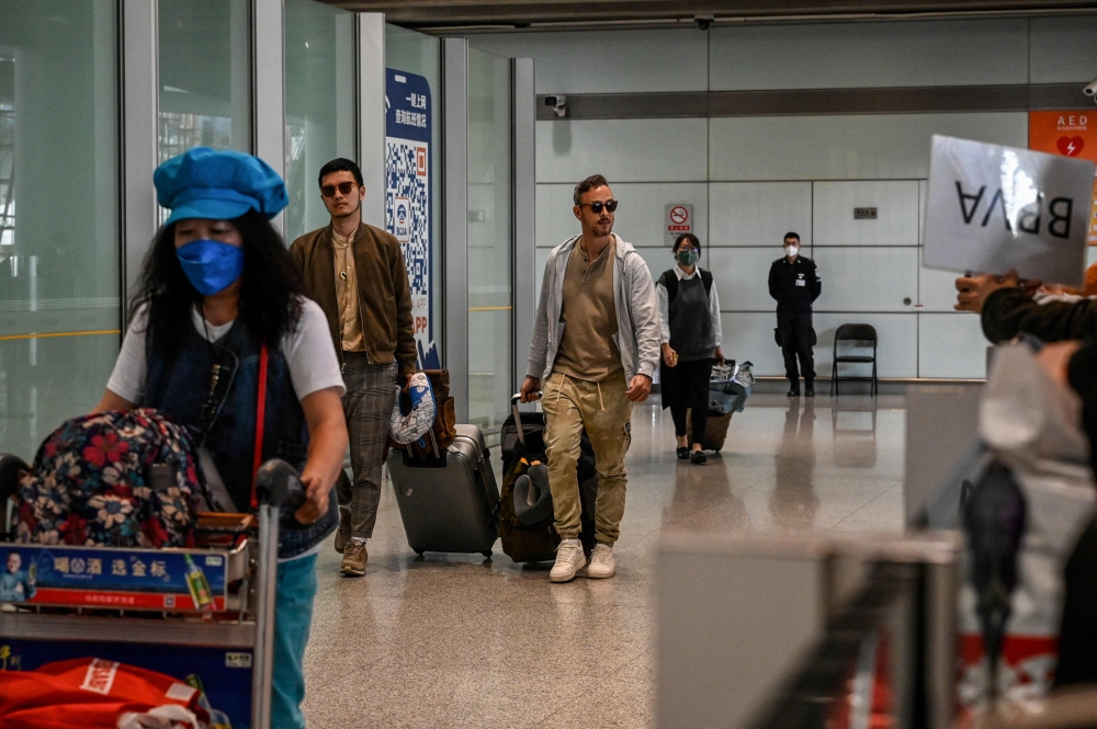 Passengers walk through the arrivals hall for international flights at the Capital International Airport in Beijing on March 14, 2023. Photo by Jade GAO / AFP

