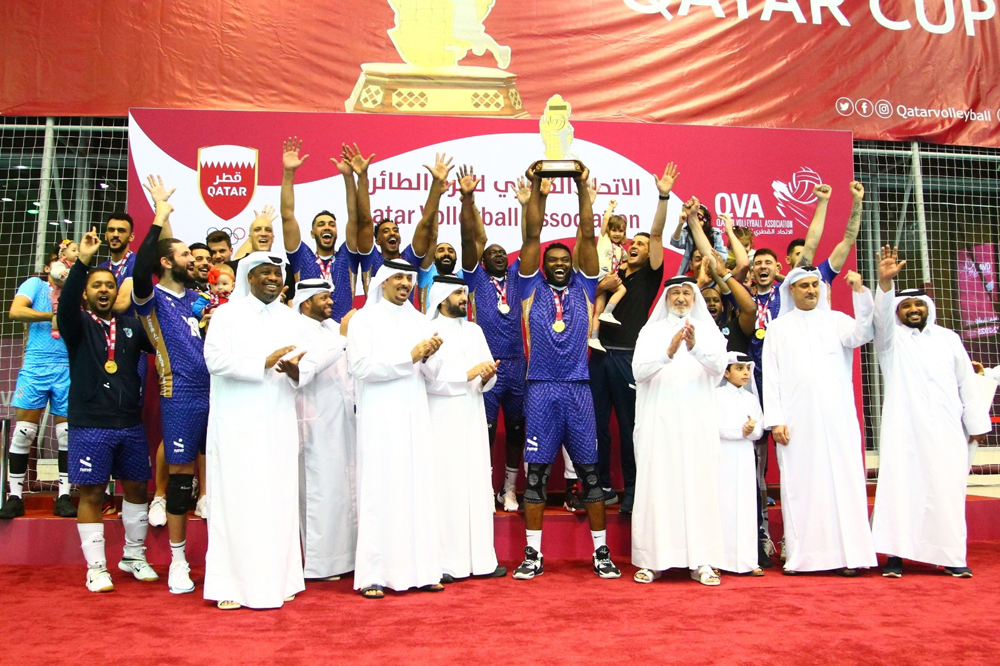 First Vice-President of the Qatar Olympic Committee Mohamed Yousef Al Mana and Qatar Volleyball Association President Ali Ghanem Al Kuwari applaud as Police players and officials celebrate with the trophy. 