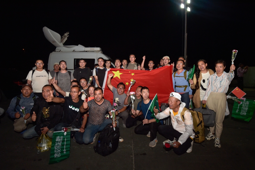 Chinese citizens evacuated from Sudan deploy a large national flag and upon their arrival at King Faisal navy base in Jeddah on April 26, 2023. Photo by Amer HILABI / AFP