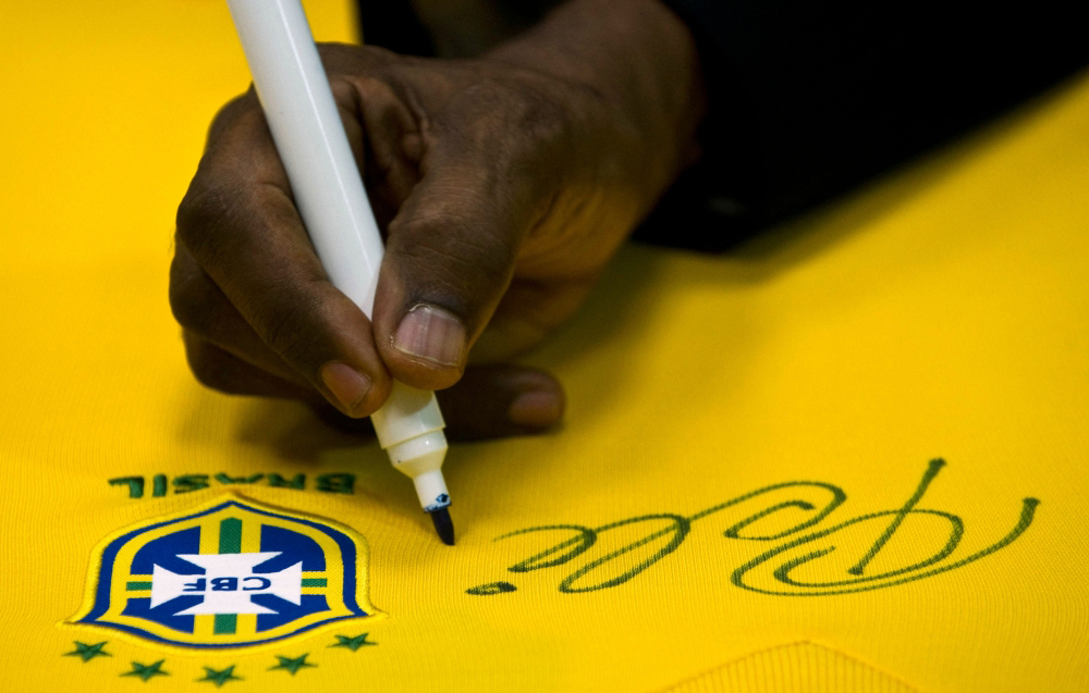 Brazilian football legend Edson Arantes do Nascimento, known as Pele, signs a Brazilian national team shirt during a press conference at Volkswagen plant in Sao Bernardo do Campo, in the metropolitan area of Sao Paulo, Brazil. Photo by Nelson ALMEIDA / AFP

