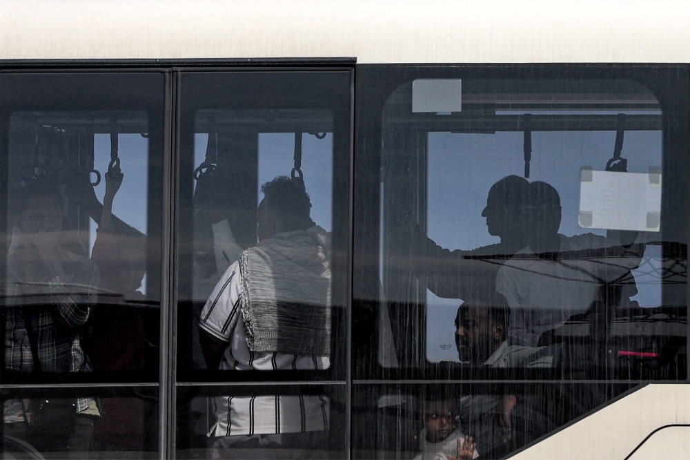 Civilians evacuated from Sudan via a British Royal Air Force plane ride a bus to the terminal at Larnaca International Airport in Cyprus on April 26, 2023. Photo by Christina ASSI / AFP