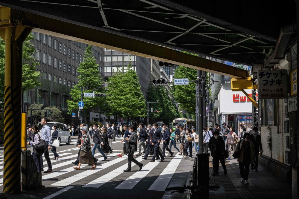 People cross a street in Yurakucho district of Tokyo on April 28, 2023. Photo by Yuichi YAMAZAKI / AFP