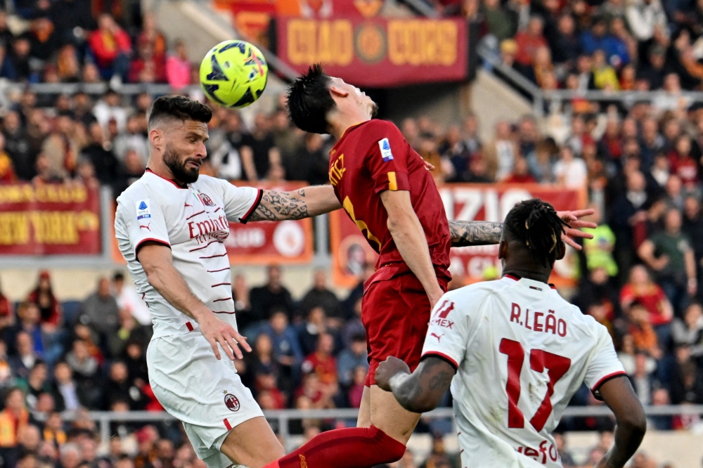 AC Milan's French forward Olivier Giroud (L) heads the ball during the Italian Serie A football match between AS Rome and AC Milan at the Olympic stadium in Rome on April 29, 2023. (Photo by Alberto PIZZOLI / AFP)