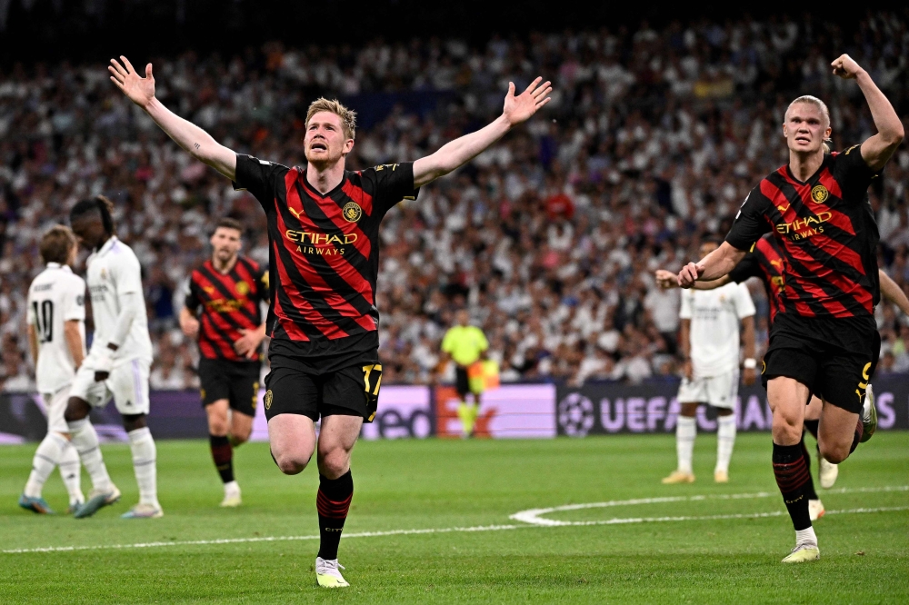 Manchester City's Belgian midfielder Kevin De Bruyne (L) next to Manchester City's Norwegian striker Erling Haaland celebrates scoring his team's first goal during the UEFA Champions League semi-final first leg football match between Real Madrid CF and Manchester City at the Santiago Bernarr stadium in Madrid on May 9, 2023. (Photo by JAVIER SORIANO / AFP)
