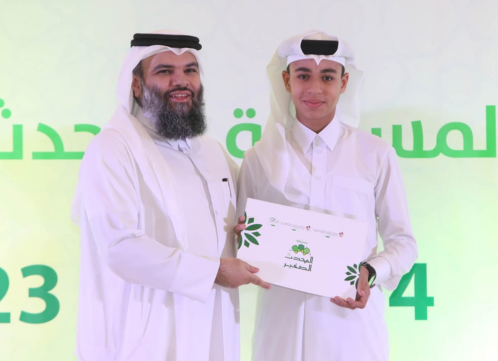 Dr. Sheikh Khalid bin Mohammed bin Ghanem Al Thani, Director of General Department of Endowments honouring a winner of Al Muhaddis Al Saghir competition during a ceremony.