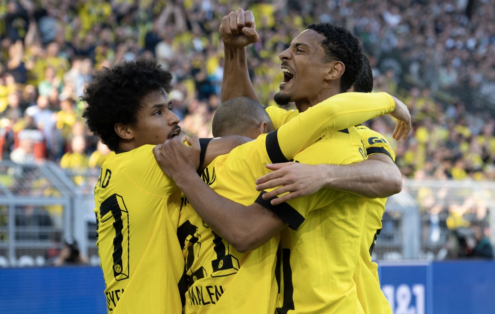 Dortmund's Dutch forward Donyell Malen (C) is congratulated by Dortmund's German forward Karim Adeyemi (L) and Dortmund's French forward Sebastien Haller (R) after scoring the 1-0 goal during the German first division Bundesliga football match between BVB Borussia Dortmund and Borussia Moenchengladbach in Dortmund, western Germany on May 13, 2023. (Photo by INA FASSBENDER / AFP) 
