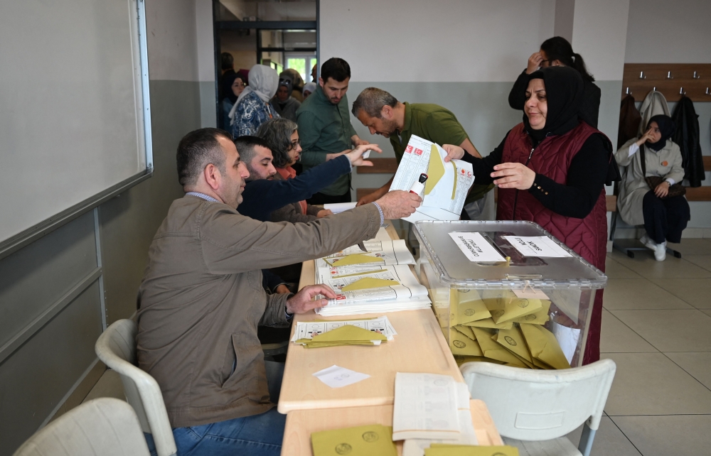A woman takes ballots at a polling station in Istanbul to vote in the parliamentary and presidental elections in Turkey, on May 14, 2023.  Photo by OZAN KOSE / AFP
