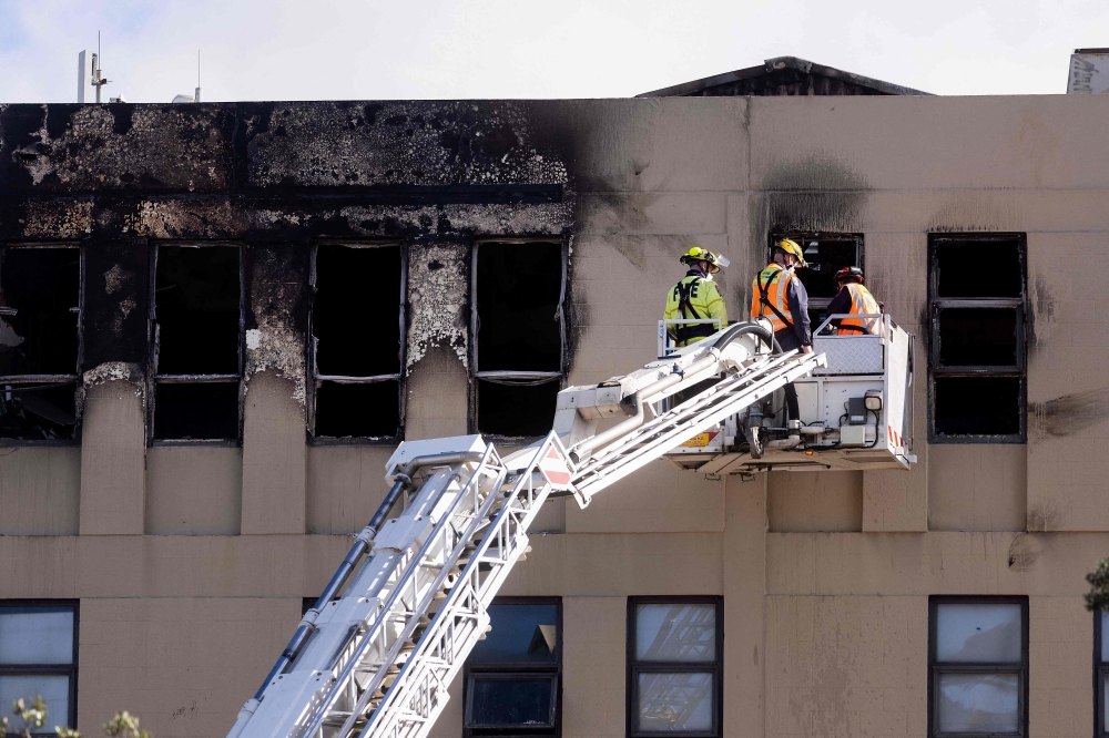 Firefighters inspect the Loafers Lodge hostel where a fire broke out a day earlier in the suburb of Newtown in Wellington on May 17, 2023. Photo by Marty MELVILLE / AFP