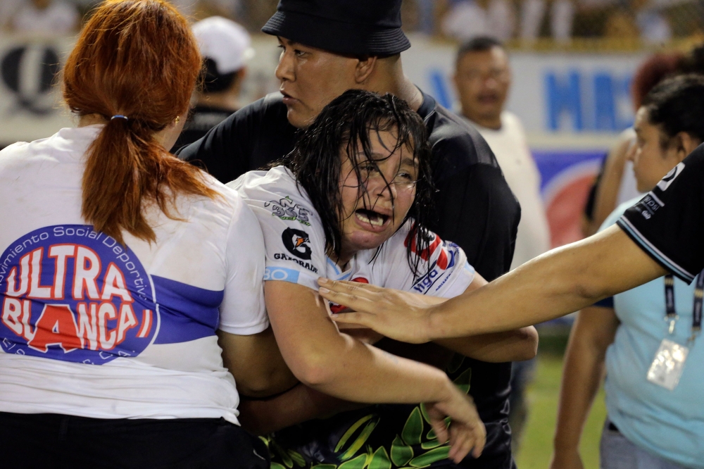 A woman is held by other as she cries following a stampede during a football match between Alianza and FAS at Cuscatlan stadium in San Salvador, on May 20, 2023. (Photo by Milton Flores / AFP)