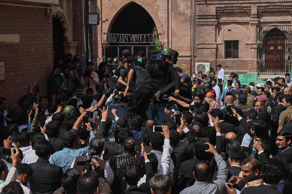 Security personnel and supporters of former prime minister Imran Khan gather around his vehicle upon his arrival in High court in Lahore on May 15, 2023. (Photo by Arif Ali / AFP)
