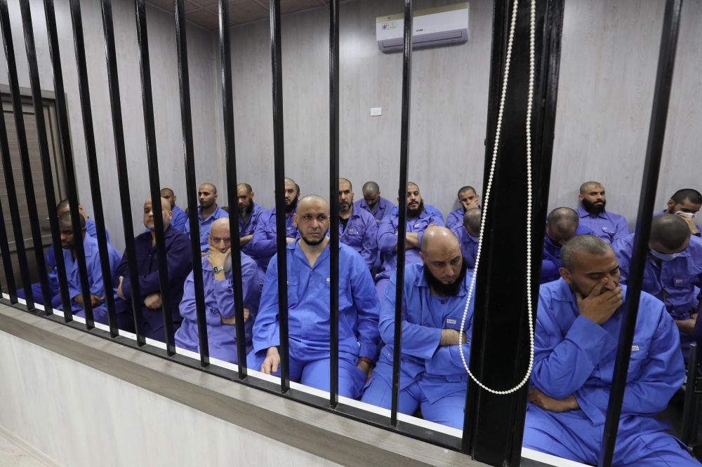 Jihadists accused of being members of the Islamic State (IS) group sit in the defendant booth during their trial, in the northwestern Libyan city of Misrata on May 29, 2023. (Photo by Mahmud Turkia / AFP)