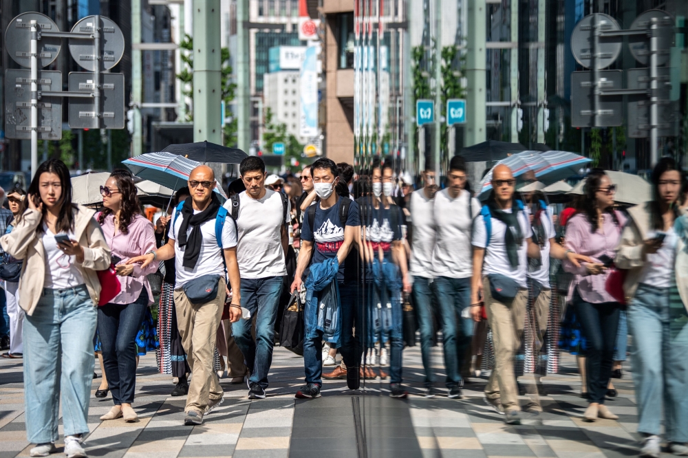 (Files) Pedestrians walk on the street in Ginza district in Tokyo on April 20, 2023. 