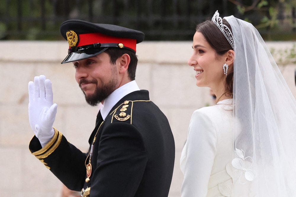 Jordan's Crown Prince Hussein and his wife Saudi Rajwa al-Seif leave in a convoy following their royal wedding ceremony in Amman on June 1, 2023. (Photo by Khalil Mazraawi / AFP)
