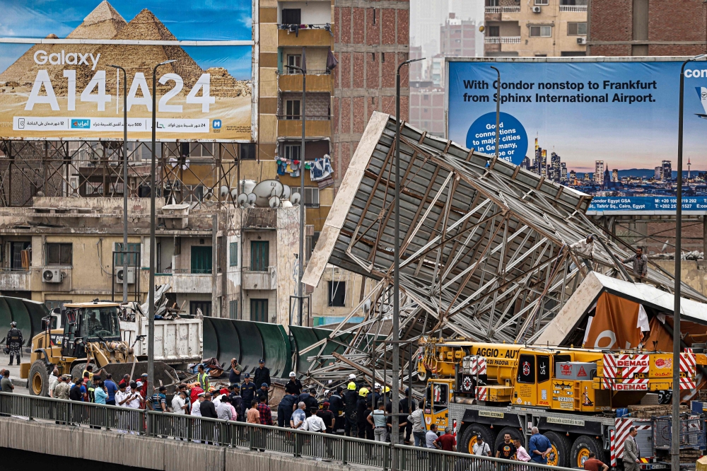 TOPSHOT - Police and civil defence gather as a collapsed billboard is removed from the October 6 overpass bridge in the Ghamra neighbourhood in central Cairo on June 1, 2023 during a sandstorm. (Photo by Khaled DESOUKI / AFP)