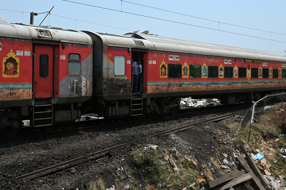 A passenger looks out from a carriage of a long-distance train as it runs on the newly restored track at the accident site of a recent three-train collision near Balasore, about 200 km (125 miles) from the state capital Bhubaneswar in the eastern state of Odisha, on June 5, 2023. Photo by Punit PARANJPE / AFP
