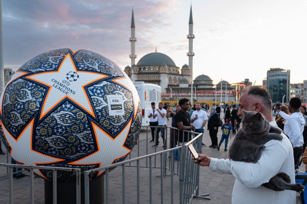 A man takes a picture of a giant replica of the Champions League soccer ball at Taksim Square on June 9, 2023 on the eve of the UEFA Champions League final between Inter Milan and Manchester City. (Photo by Umit Turhan Coskun / AFP)