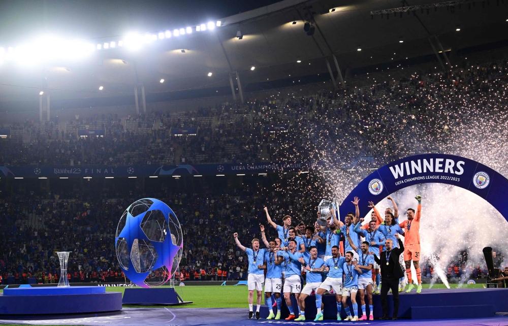 Manchester City's players lift the European Cup trophy as they celebrate on the podium after winning the UEFA Champions League final football match between Inter Milan and Manchester City at the Ataturk Olympic Stadium in Istanbul, on June 10, 2023. (Photo by Marco Bertorello / AFP)