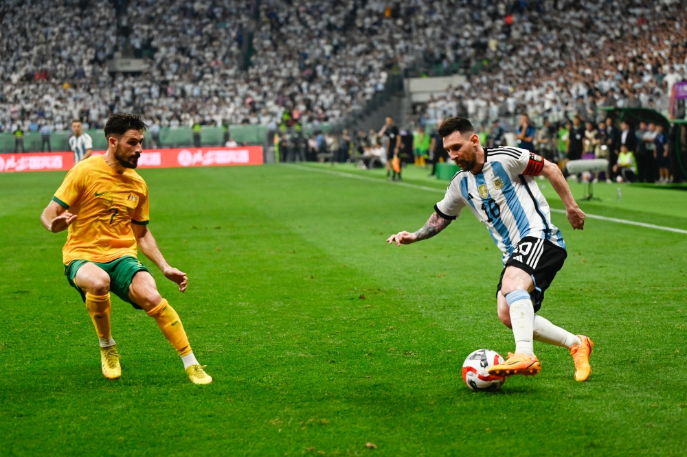 Argentina's Lionel Messi (R) fights for the ball with Australia's Mathew Leckie during a friendly football match between Australia and Argentina at the Workers' Stadium in Beijing on June 15, 2023. (Photo by Pedro Pardo / AFP)