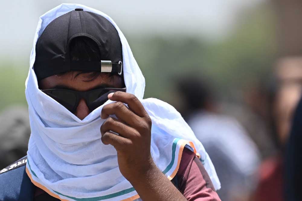 File photo: A man uses a scarf to shelter from the heat during a hot day in New Delhi on April 19, 2023. (Photo by Arun SANKAR / AFP)