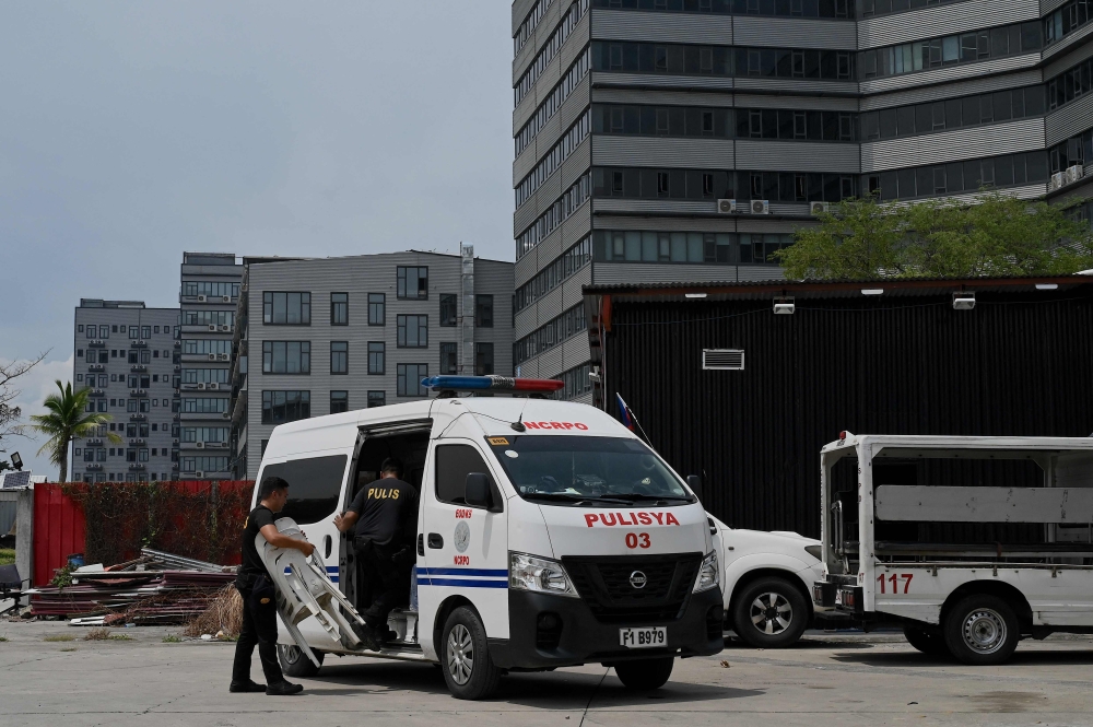 Policemen are seen on standby inside a compound, where police raided buildings in Metro Manila on June 27, 2023. (Photo by JAM STA ROSA / AFP)
