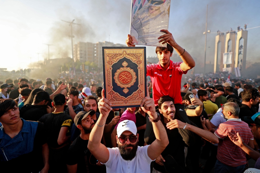 A supporter of Iraq's Sadrist movement holds up the Holy Quran outside the Swedish embassy in Baghdad on June 30, 2023. (Photo by Ahmad Al-Rubaye / AFP)