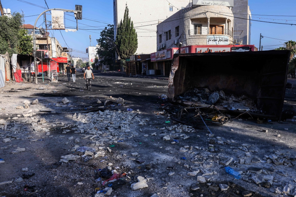 People walk along a street in the occupied West Bank city of Jenin on July 4, 2023, a day after an Israeli military operation. (Photo by Ronaldo SCHEMIDT / AFP)
