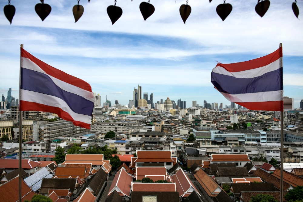 (FILES) This photo taken on June 26, 2023 shows Thai flags fluttering in the wind as the backdrop of Bangkok skyline seen from the Wat Saket Buddhist temple. (Photo by Amaury PAUL / AFP)
