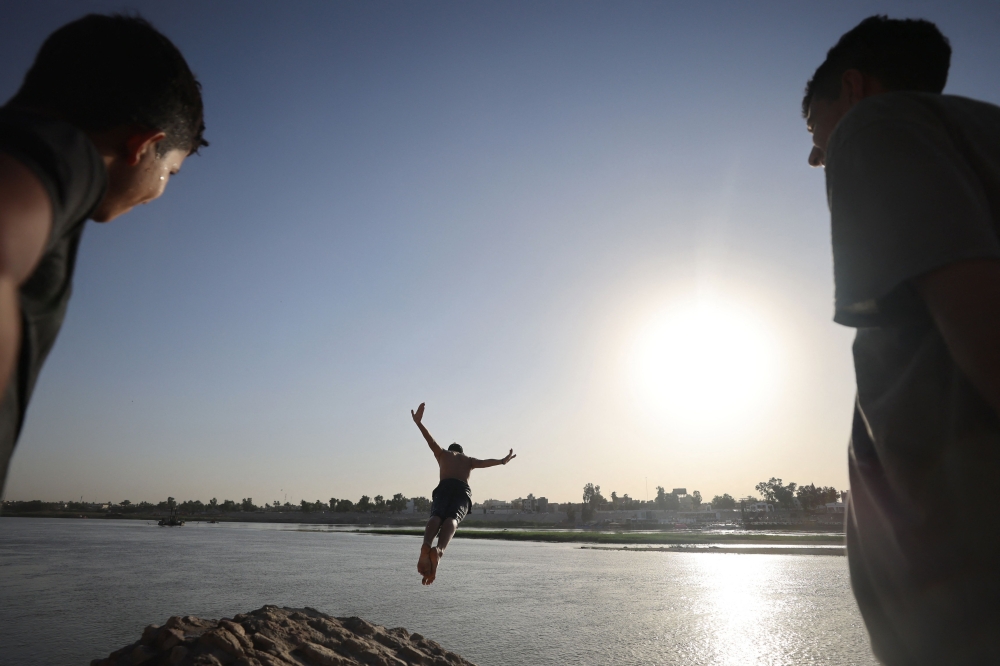 An Iraqi dives into the waters of the Tigris river in Baghdad on July 12, 2023, as temperatures soared past 45 degrees Celsius. (Photo by Ahmad AL-RUBAYE / AFP)
