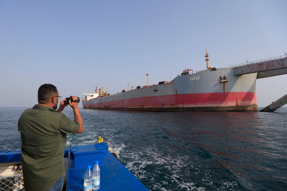 A man snaps a picture of the beleaguered Yemen-flagged FSO Safer oil tanker in the Red Sea off the coast of Yemen's contested western province of Hodeida on July 15, 2023. (Photo by Mohammed Huwais / AFP)